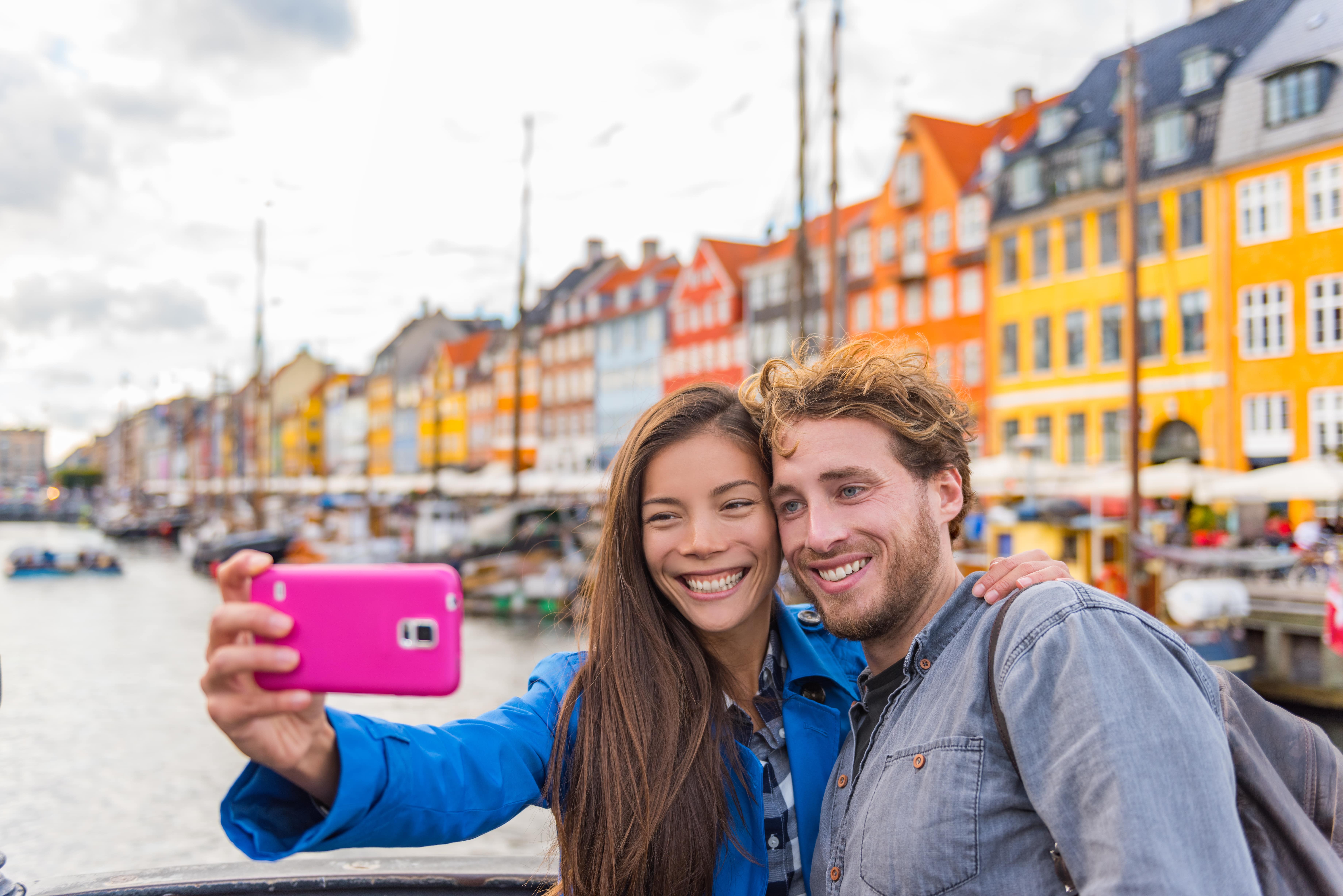 Copenhagen travel couple tourists taking selfie photo with phone camera.