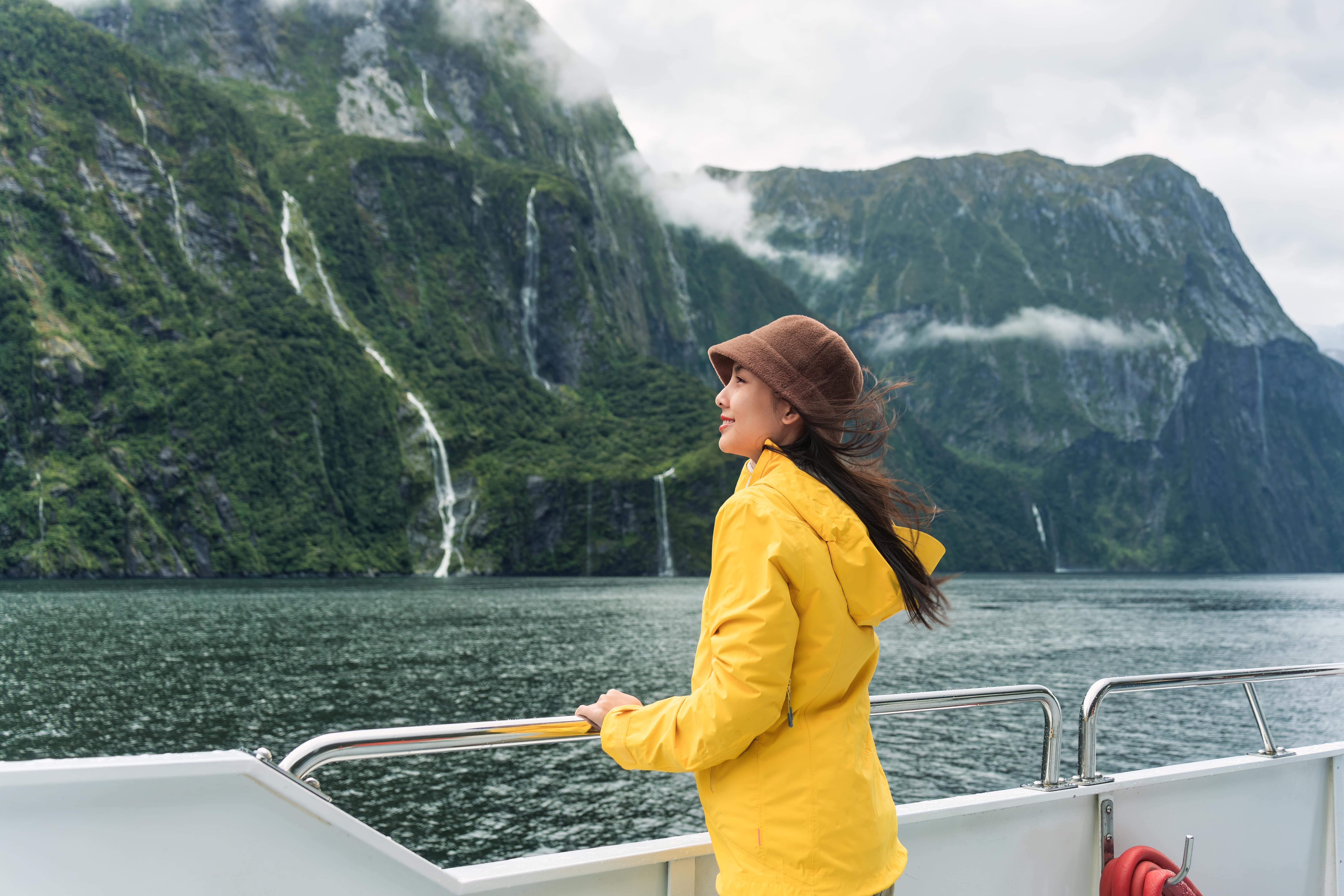 Asian woman enjoying the view of Milford Sound during ferry cruise on vacation at New Zealand