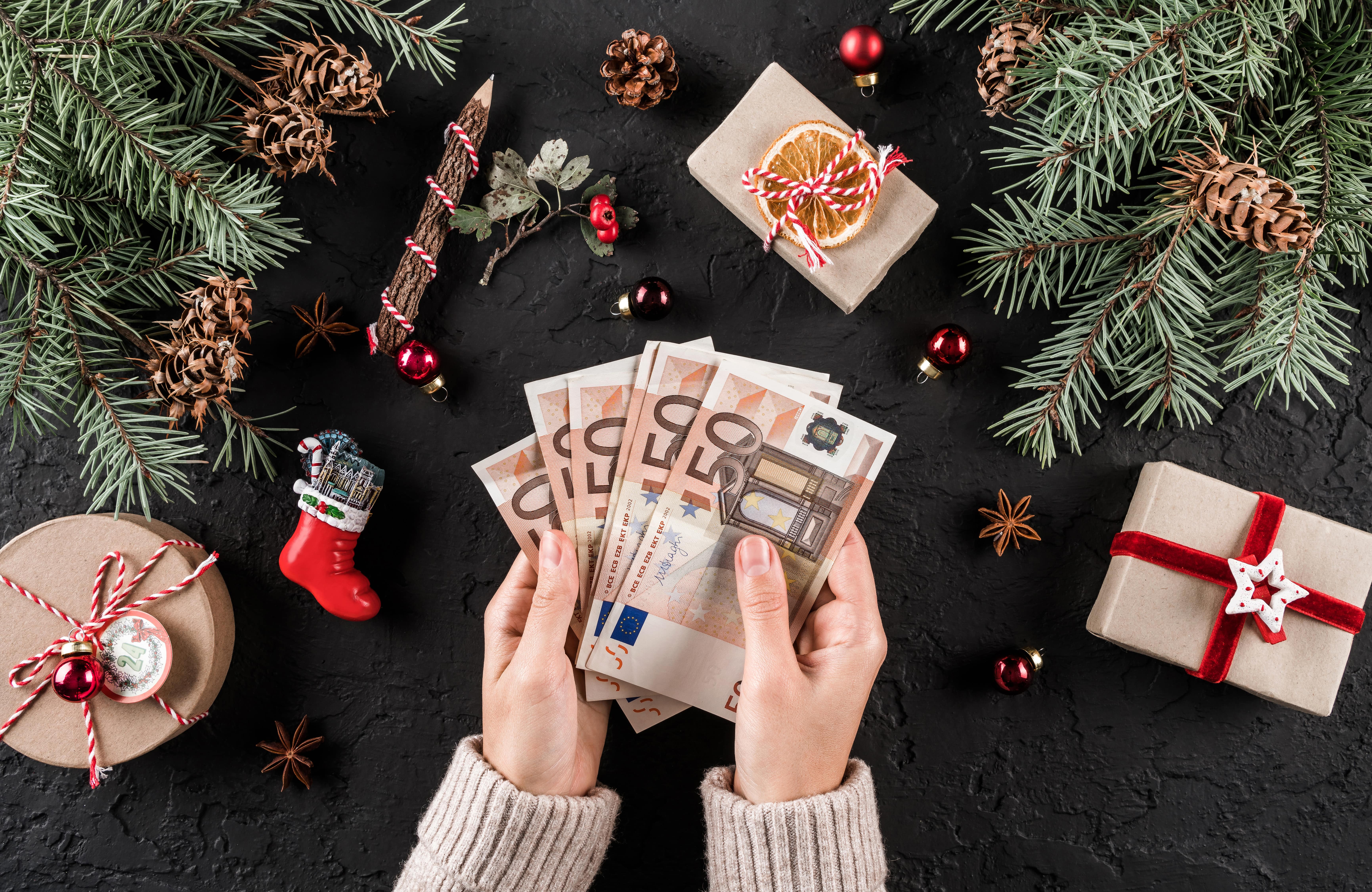 Female hands hold money for shopping on Christmas background 